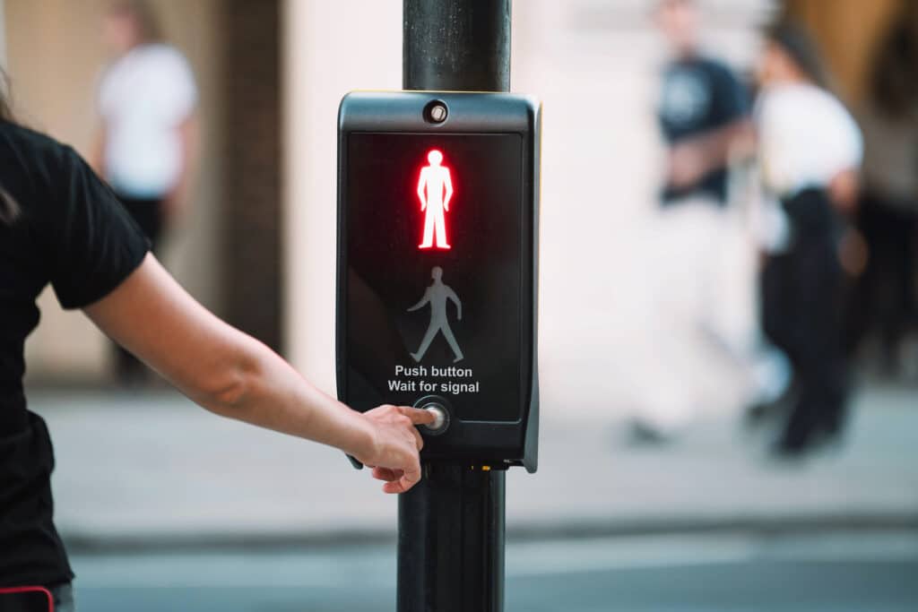 pedestrian pressing the button of a walk signal
