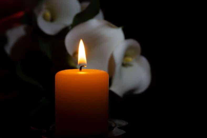 candle lit at a funeral with flowers in background