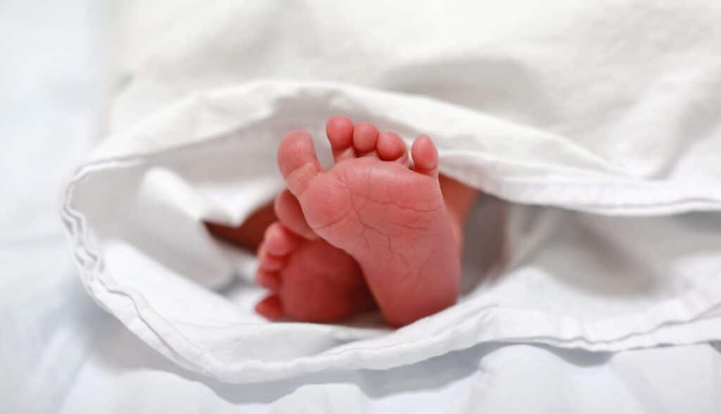 newborn under a blanket showing its feet