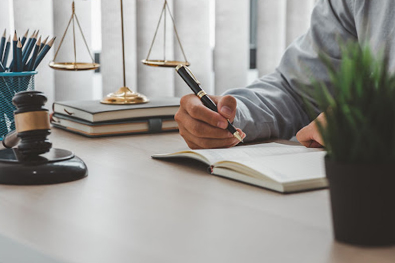 wrongful death attorney writing in a law book at a table