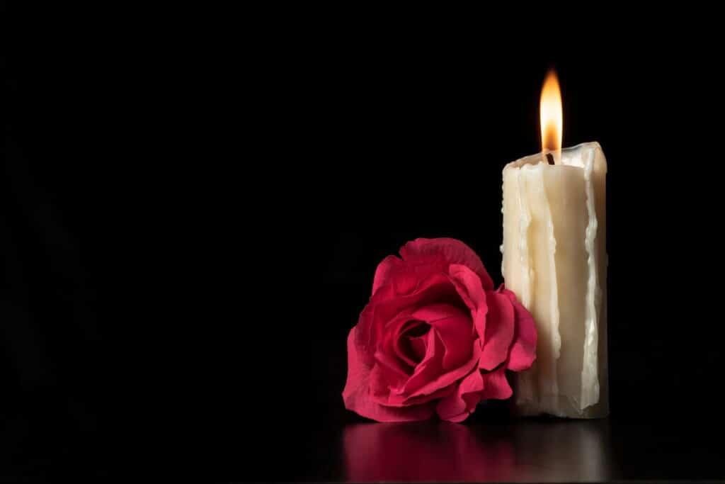 One red flower next to a lit candle after a wrongful death occured.
