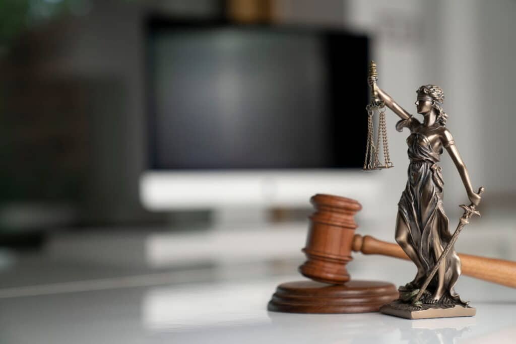 A Lady Justice statue and a gavel on a car accident attorney's desk.