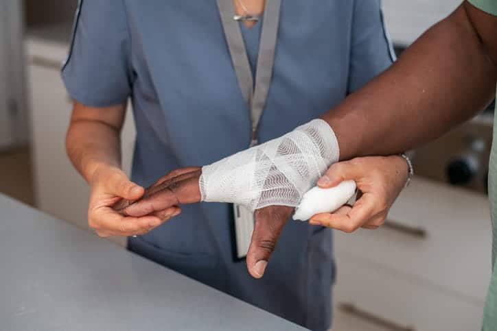 A nurse wrapping gauze around a person with a burn injury on their hand. 