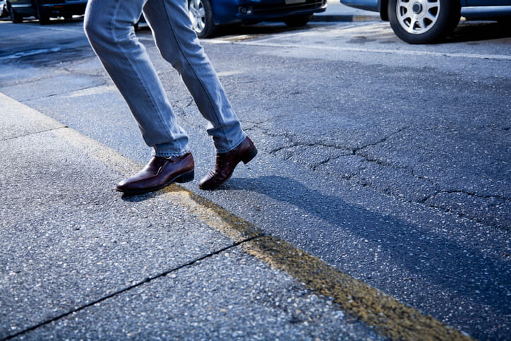 A person crossing the road while there are vehicles.