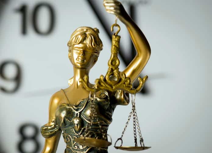 A Lady Justice statue in front of a clock.