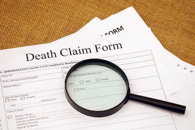 A magnifying glass on top of a "Death Claim Form." 